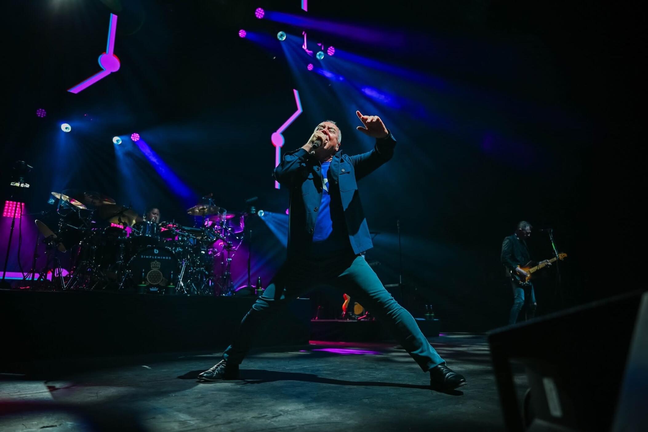 Simple Minds’ Jim Kerr (center) rouses the audience at the Cynthia Woods Mitchell Pavilion in the Woodland, Texas, on May 31, 2025.