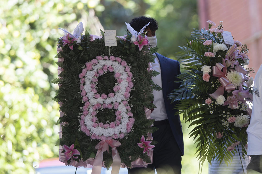 A man carries flowers into a viewing for 8-year-old Secoriea Turner, who was fatally shot in Atlanta on July 4th near the Wendy's site where Rayshard Brooks was killed the previous month Tuesday, July 14, 2020, in South Fulton, Ga. 