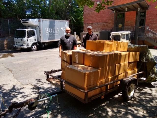 Employees from one of the Atlanta Community Kitchen Project's partners, Bold Catering & Design, stand by a ready-to-go shipment of prepared meals.