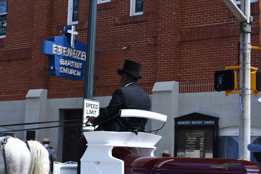 The horse-drawn carriage with C.T. Vivian's body drives past historic Ebenezer Baptist Church on Auburn Ave.