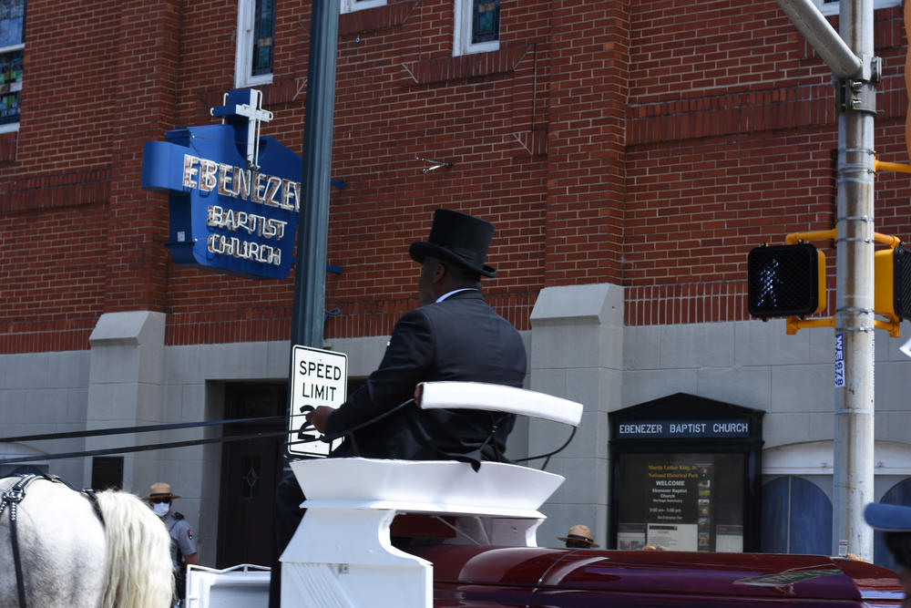 The horse-drawn carriage with C.T. Vivian's body drives past historic Ebenezer Baptist Church on Auburn Ave.