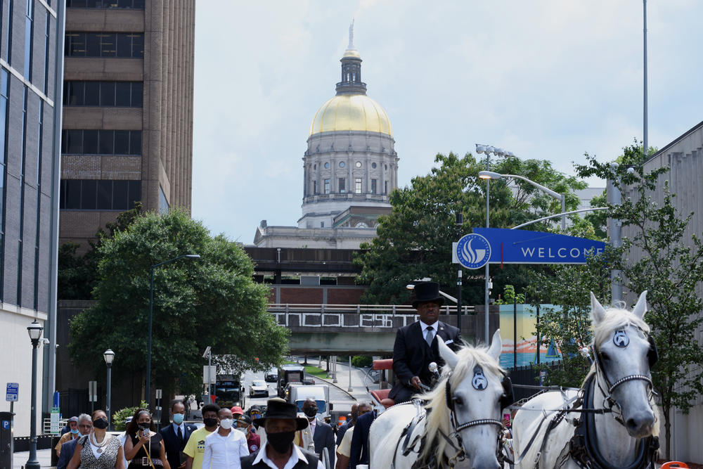 Family and friends of the late C.T. Vivian follow his casket down Piedmont Avenue in Atlanta.