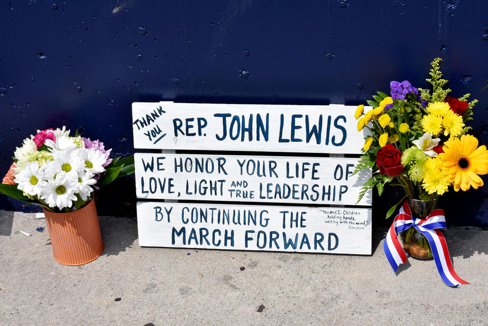 A sign placed at the base of a John Lewis mural in Atlanta.