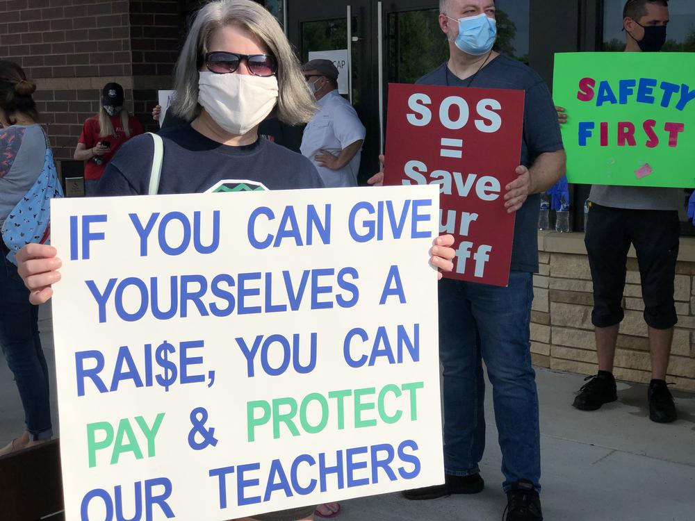 Julie Ball holds a sign outside the Cherokee County School Board meeting Thursday July 16, 2020.