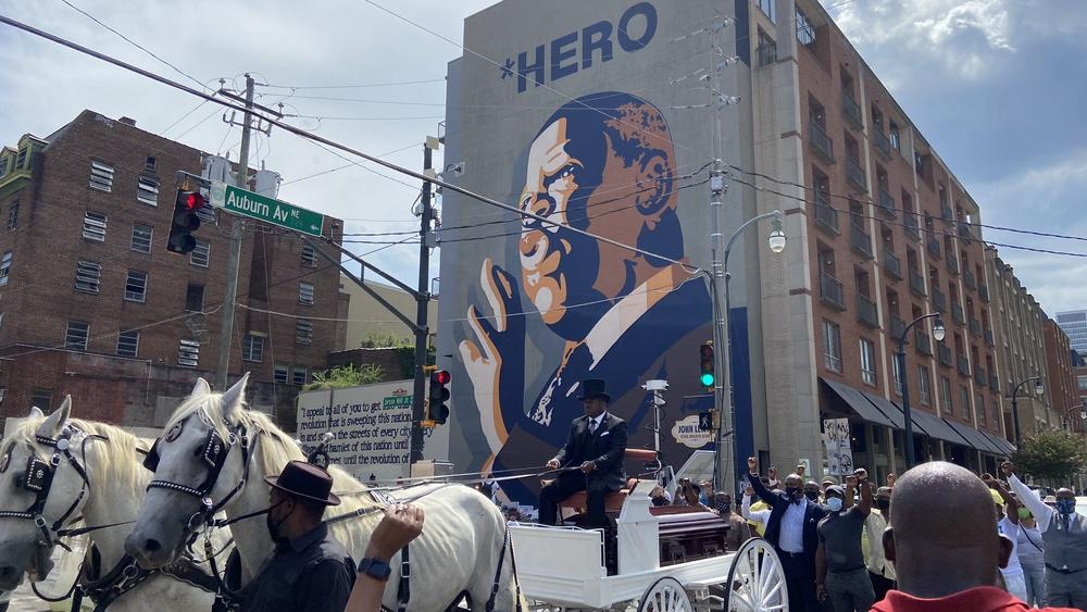 The casket of John Lewis passes by a mural in his likeness near downtown Atlanta.