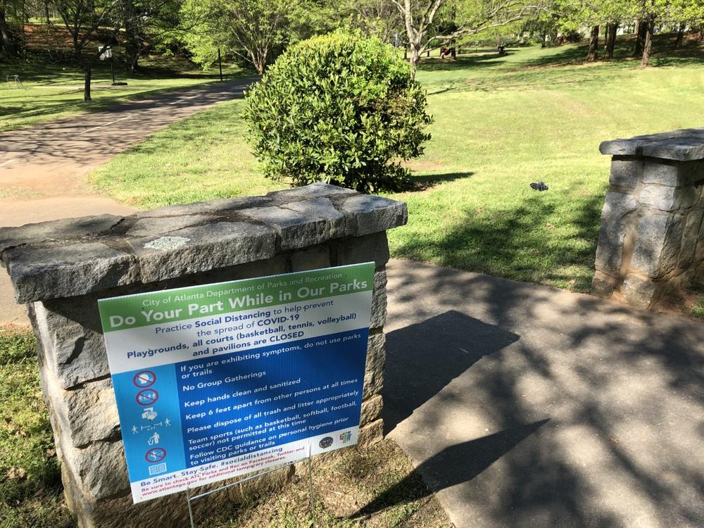 A sign outside of a Atlanta park tells visitors to wear a mask.