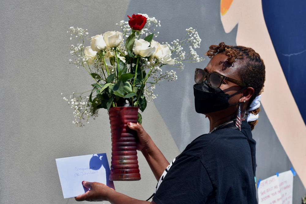 Phyllis Dent-Brown lays flowers down at the base of a John Lewis mural in Atlanta.