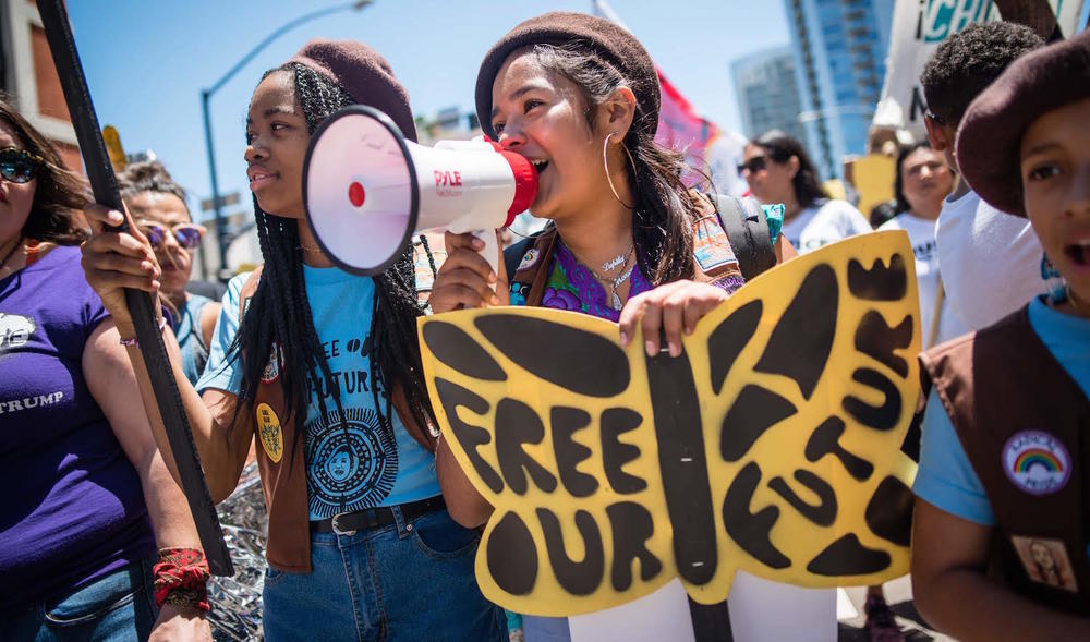 Members of the Radical Monarch troupe marching with signs.