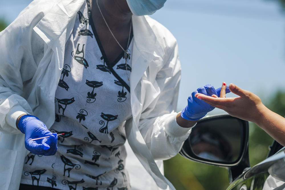 A healthcare worker administers an antibody test to a motorist