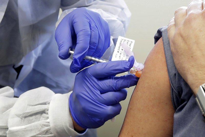 FILE - In this March 16, 2020, file photo, a subject receives a shot in the first-stage safety study clinical trial of a potential vaccine by Moderna for COVID-19, the disease caused by the new coronavirus, at the Kaiser Permanente Washington Health Research Institute in Seattle.