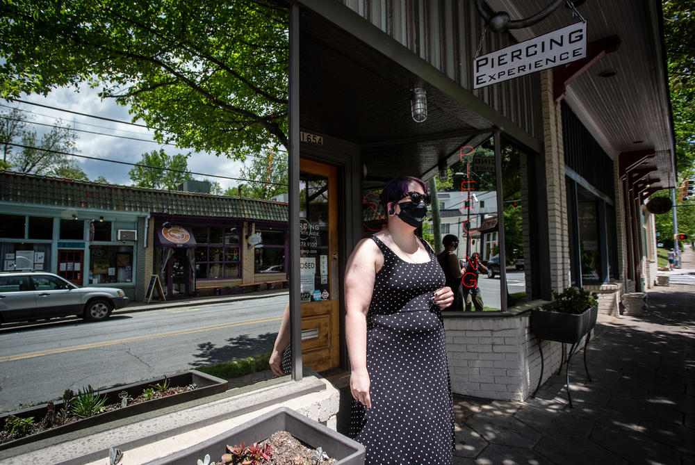 A masked women stands outside a business in Atlanta closed by the pandemic.