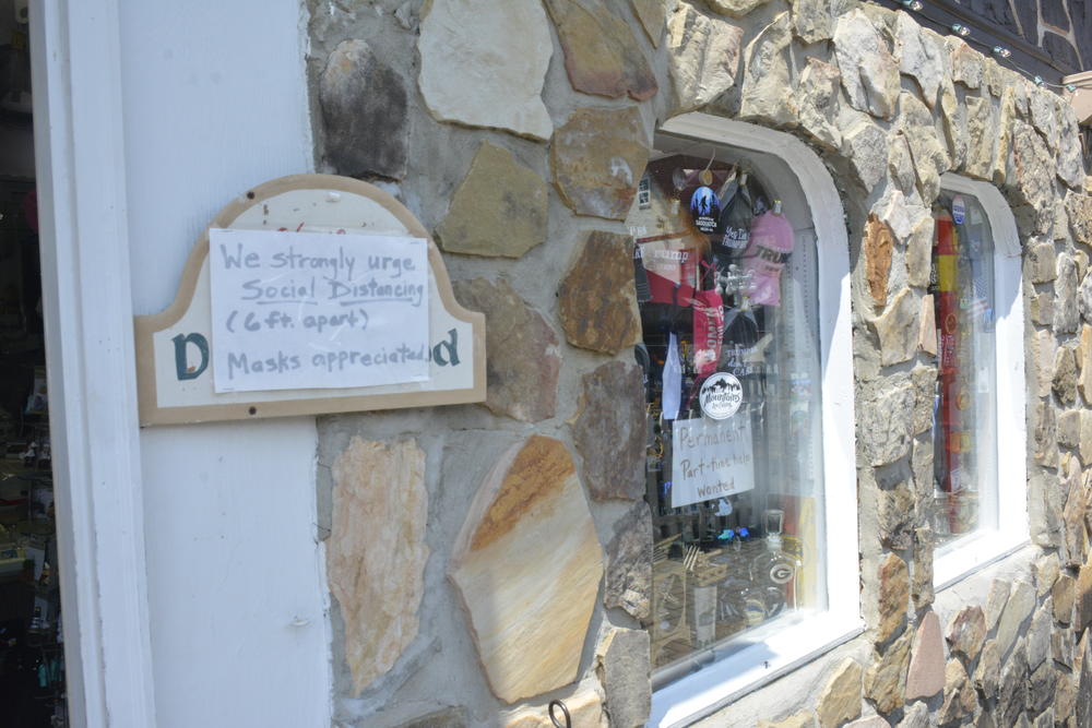 A sign encouraging social distancing next to a display of Trump 2020 hats in Helen, GA.