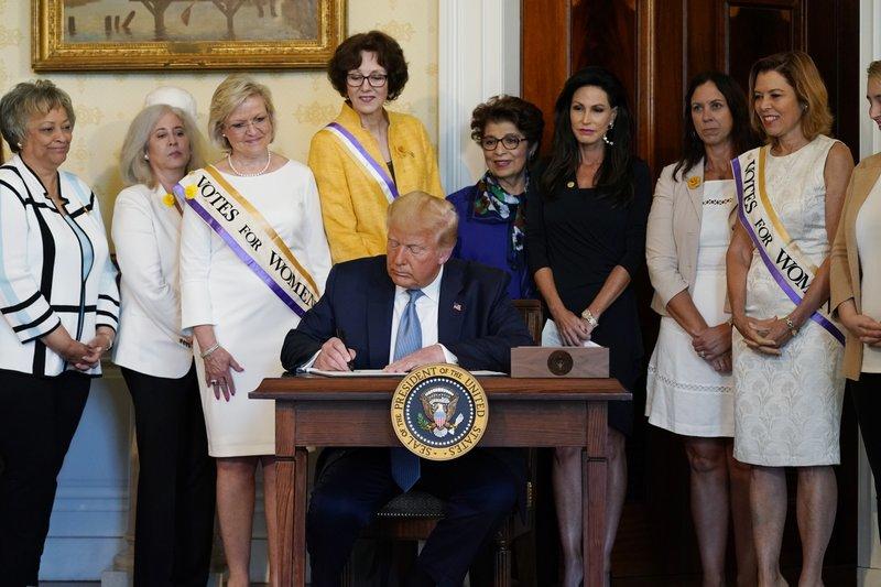 President Donald Trump signs a proclamation recognizing the 100th anniversary of the ratification of the 19th Amendment, Tuesday, Aug. 18, 2020, in the Blue Room of the White House in Washington.