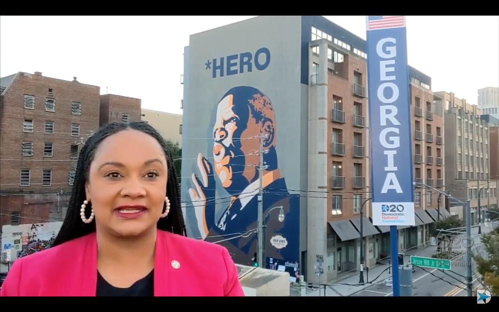 Georgia Democrat speaks to the Democratic National convention from aside a mural of Congressman John Lewis.