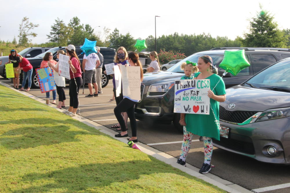 people hold signs thanking CCSD for not mandating masks