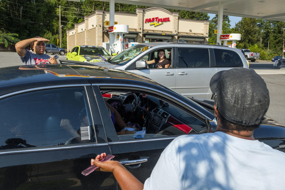 A group of parents turned away from the WiFi hotspot distribution commiserate in the gas station parking lot across the road from the Bibb Schools office. 