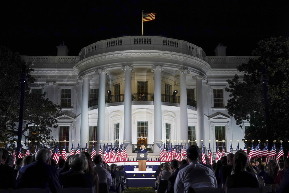 Donald Trump stands in front of the White House.