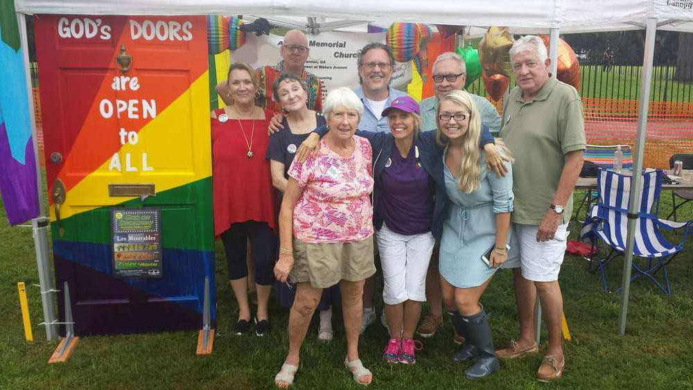 Members of Savannah's Asbury Memorial Church pose with a rainbow-painted door that says "God's Doors are Open to All"