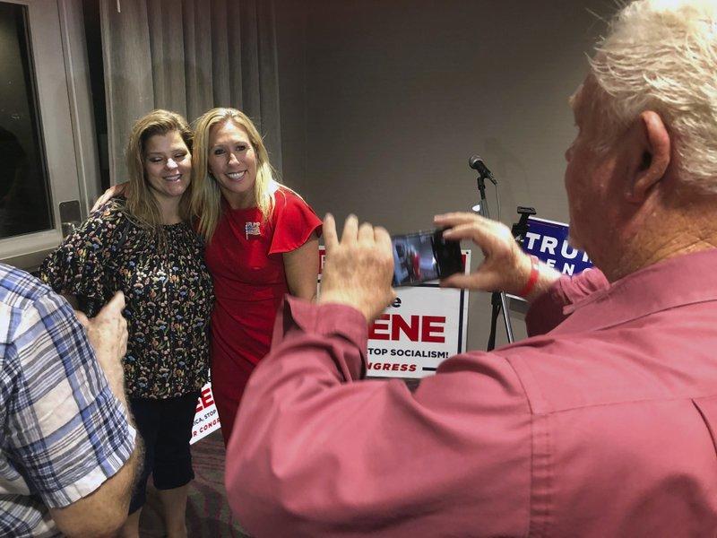 FILE - In this Tuesday, Aug. 11, 2020 file photo, Supporters take photos with construction executive Marjorie Taylor Greene, background right, late in Rome, Ga. 