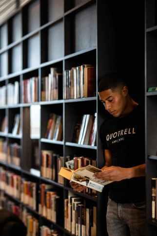 Young man reading book in library.
