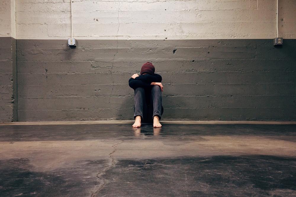 person leaning on wall with head in hands