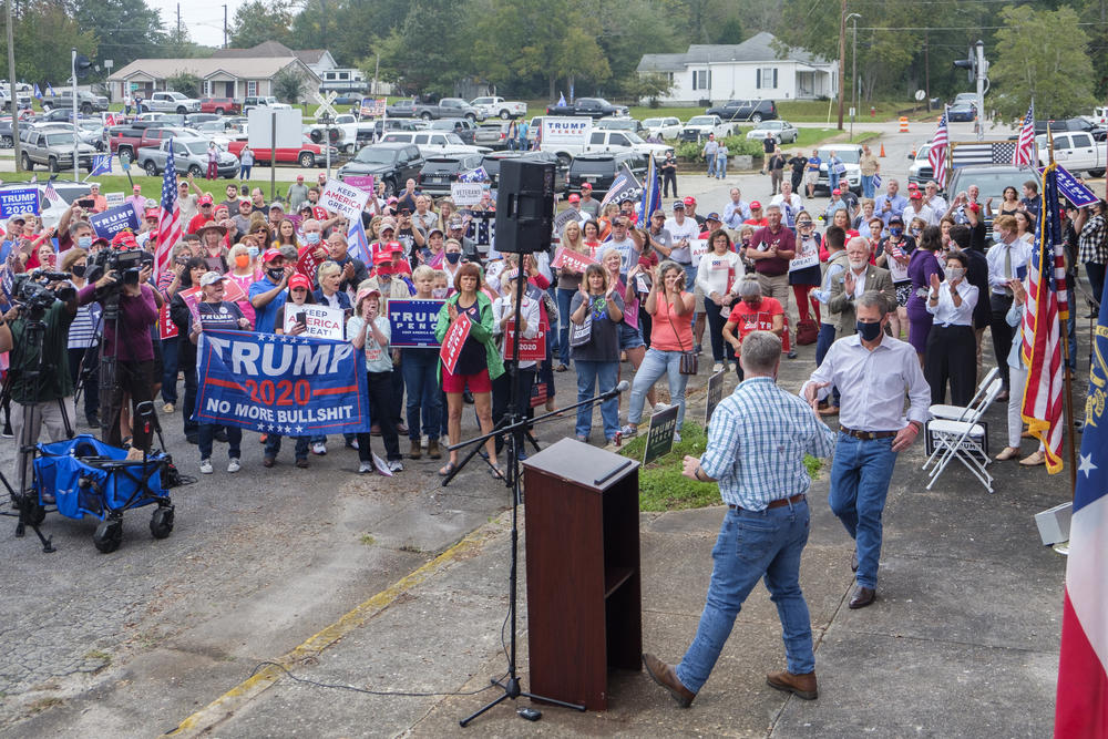 Governor Brian Kemp shakes hands with US House Representative Drew Ferguson at the podium of a Trump rally in Manchester this week. Ferguson has since tested positive for COVID-19. Kemp is quarantining. 