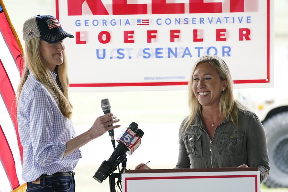 Kelly Loeffler and Majorie Taylor Greene stand on stage together.