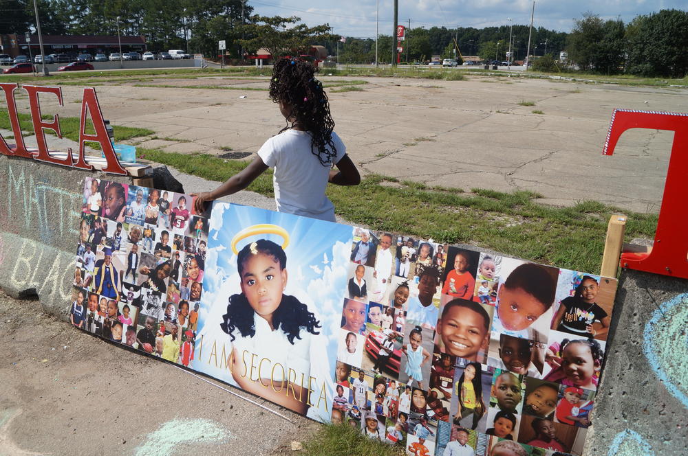 Malia Morton stands behind a collage paperboard.