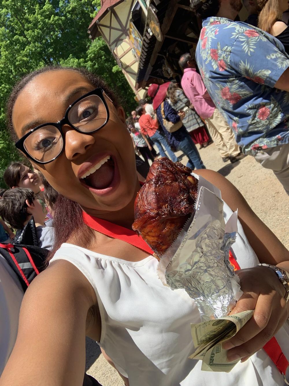 Madison McNair is smiling while holding a turkey leg at the ASL Day Festival in 2019.