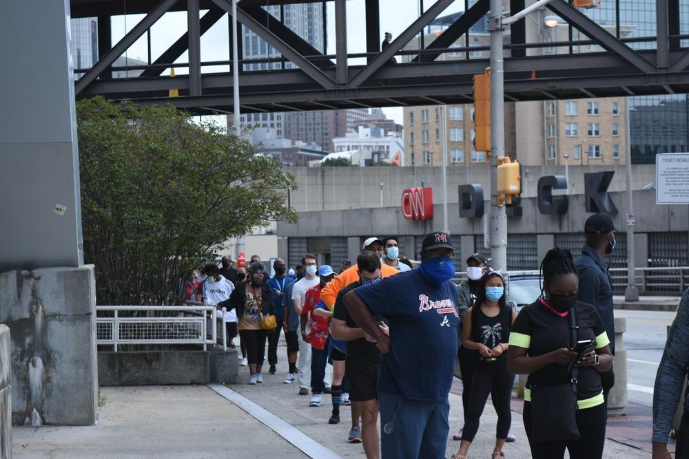 Voters wait in line outside State Farm Arena in Atlanta on the first day of in-person early voting in Georgia.