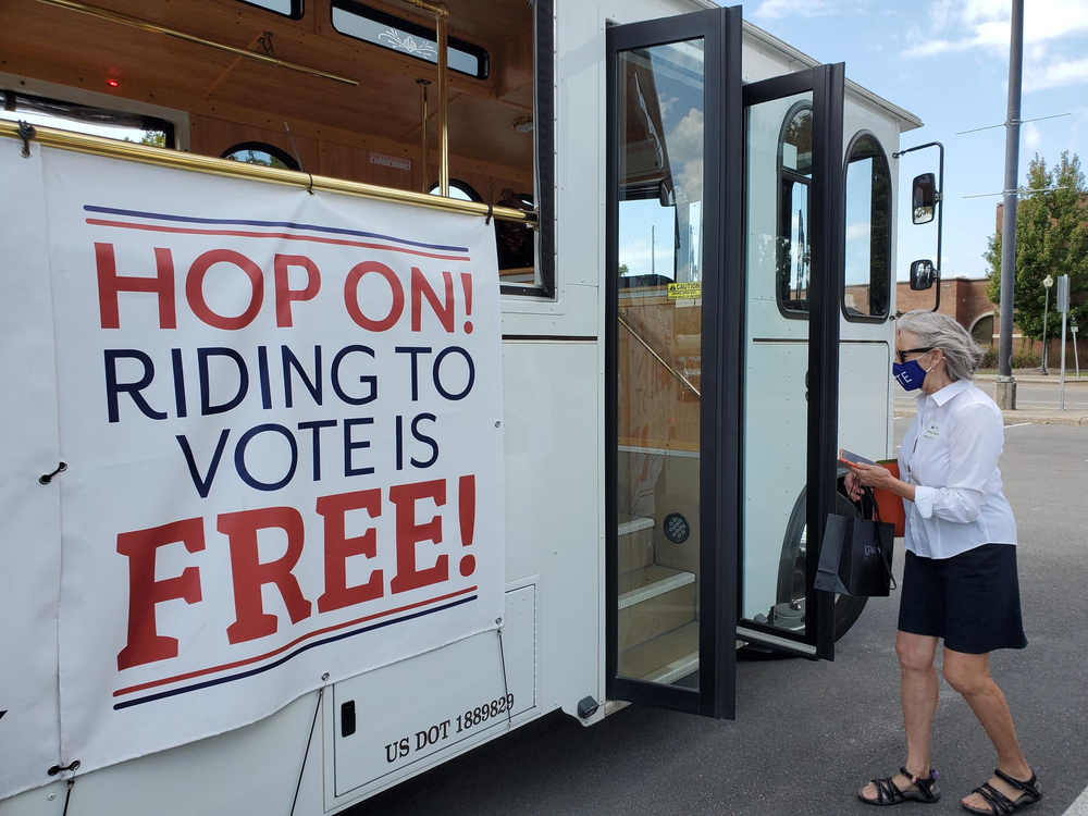 Rebecca Rolfes boards a trolley that bears a banner announcing "riding to vote is free"