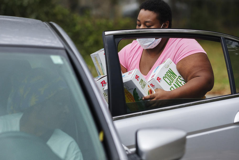 A member of Single Moms Connect lots groceries in the back of a recipient's car. According to the group Feeding American, just under half of the people accessing food aid during the COVID-19 recession are doing so for the first time in their lives. 