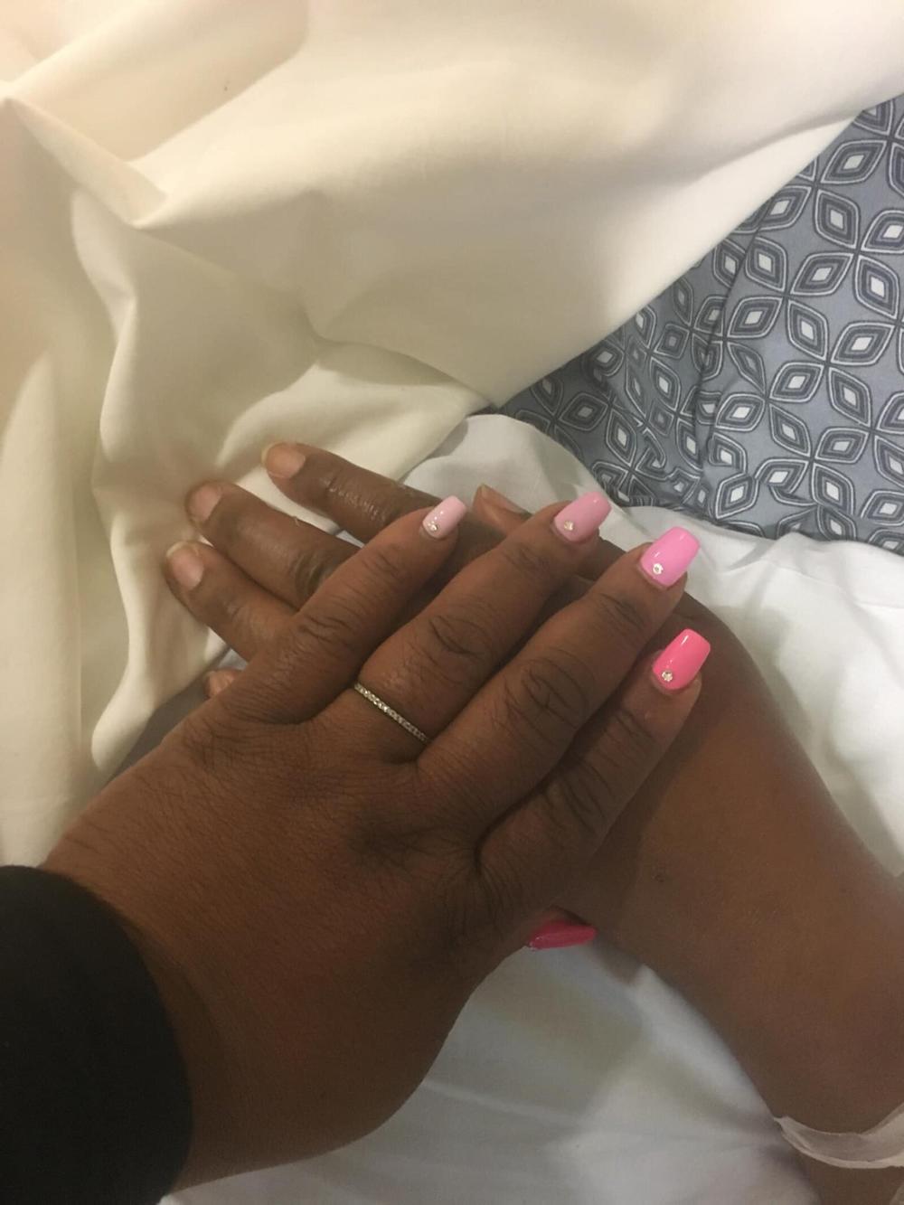 Shonte holds her sister Shonray’s hand in the hospital. 