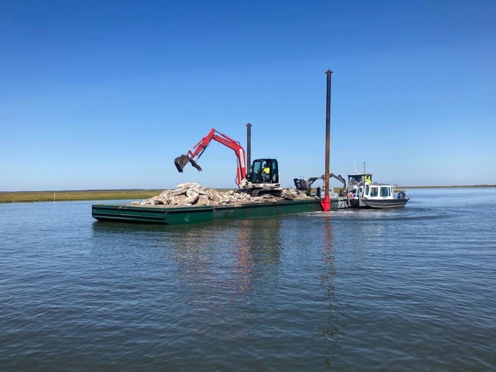 Floating equipment adding chunks of concrete to an artificial reef