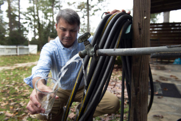 Holland checks the water from the well behind his home.