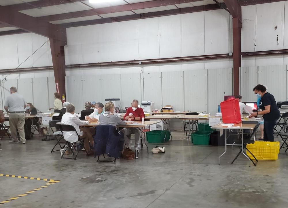 workers tabulate absentee ballots in a warehouse