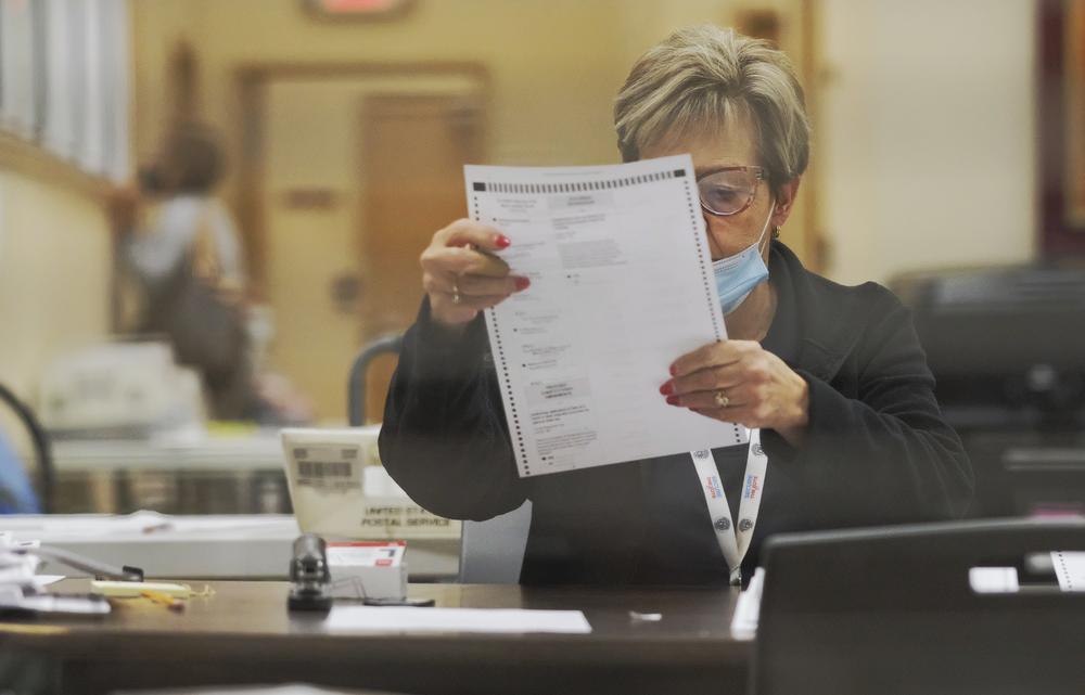 poll worker inspects absentee ballot