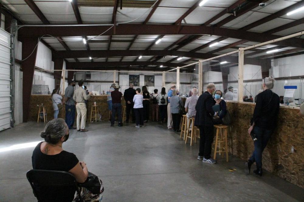 Observers stand behind a plywood and plexiglass partition to watch the counting process.