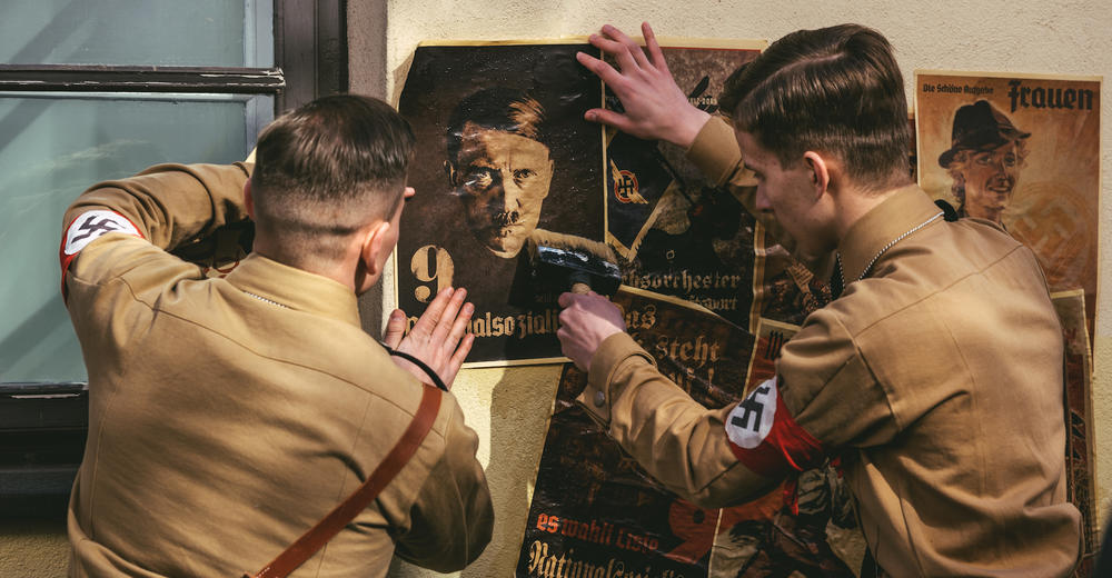 Drama Reconstruction Stormtroopers in uniforms post Hitler posters on wall.