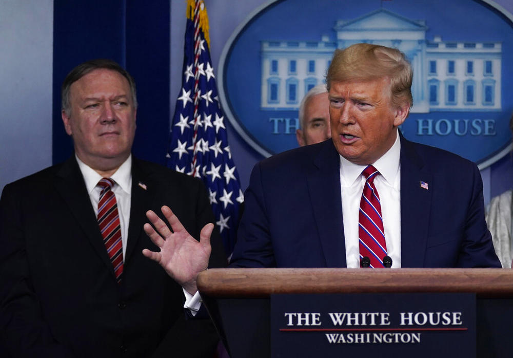 FILE - In this March 20, 2020, file photo, with Secretary of State Mike Pompeo to the rear, U.S. President Donald Trump speaks during a coronavirus task force briefing at the White House in Washington.