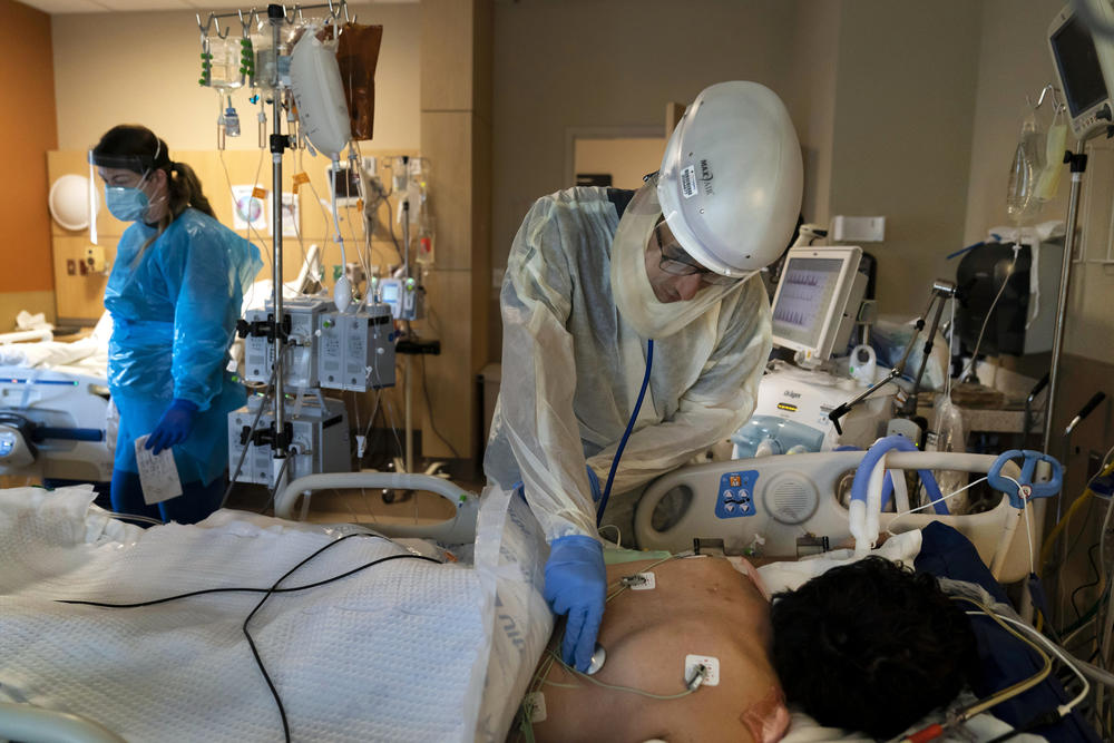 A doctor in protective gear attends to a COVID-19 patient.