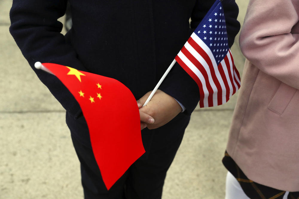 People hold Chinese and American flags as they wait for President Donald Trump and Chinese President Xi Jinping to participate in a welcome ceremony at the Great Hall of the People, Thursday, Nov. 9, 2017, in Beijing, China. (AP Photo/Andrew Harnik)