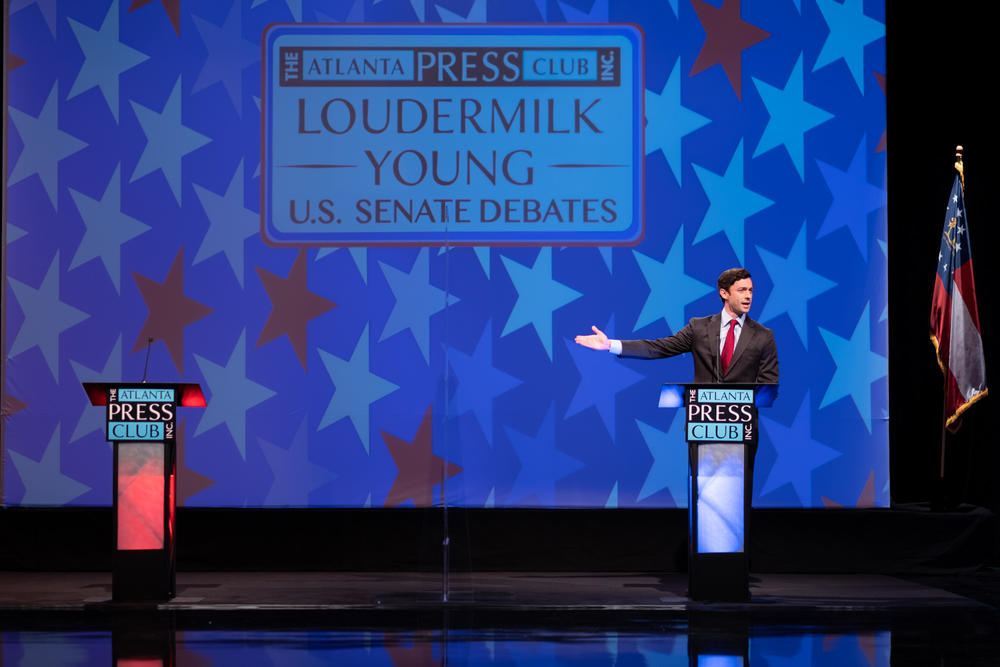 Democratic U.S. Senate nominee Jon Ossoff gestures to an empty lectern representing his opponent, Republican Sen. David Perdue, who declined to attend a debate Dec. 6, 2020.