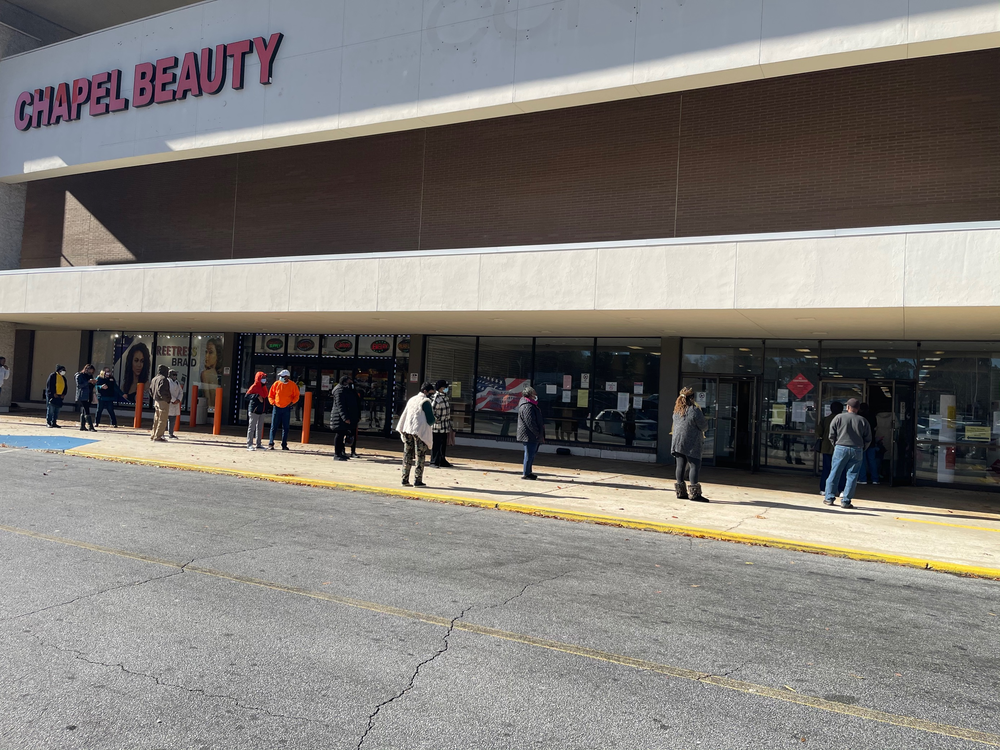 A moderately-sized line of early voters stretches outside the door of South Dekalb Mall.