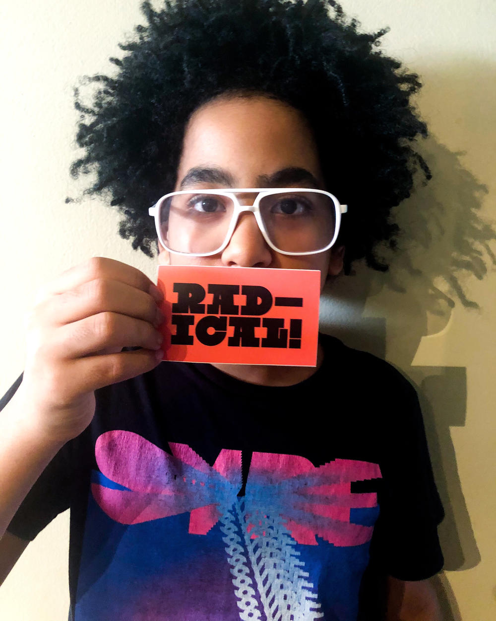 Elijah Gomez holds up one of his sticker designs that says "RADICAL!"
