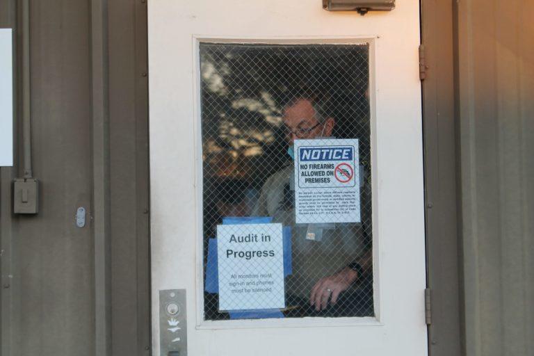 Chatham officer tapes a warning sign to notify audit observers that guns are not allowed inside the warehouse where paper ballots were being counted by hand in mid-November.