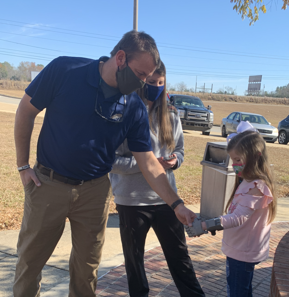 Lilly uses her new prothetic to shake her father's hand. 