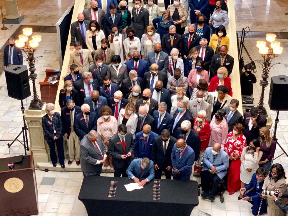 Flanked by state lawmakers, Gov. Brian Kemp signs Georgia’s hate-crimes bill into law on June 26, 2020.