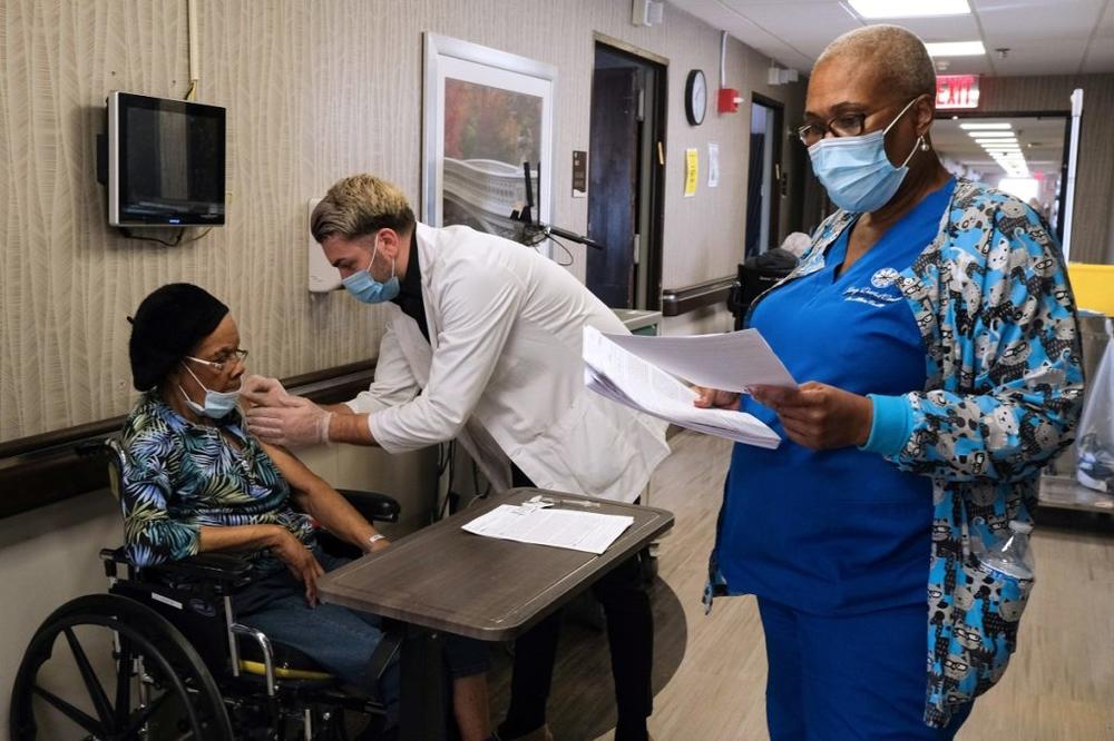 Medical professionals administering the vaccine to an elderly patient.