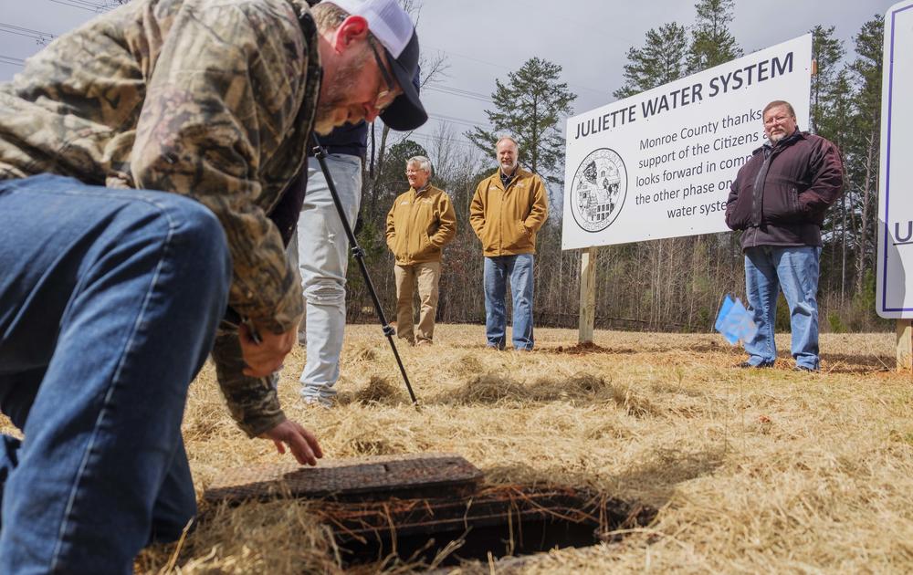 From left, Monroe County Commissioner John Ambrose, Commission Chair Greg Tapley and Monroe County resident Charles Grizzard watch as a worker turns on the water service to Grizzard’s house Tuesday. Grizzard was the first resident to get city water in a project inspired by worries about coal ash at Georgia Power’s Plant Scherer.  